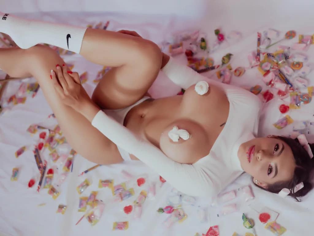 On her back, huge tits exposed, Yeline arches in submissive surrender.
