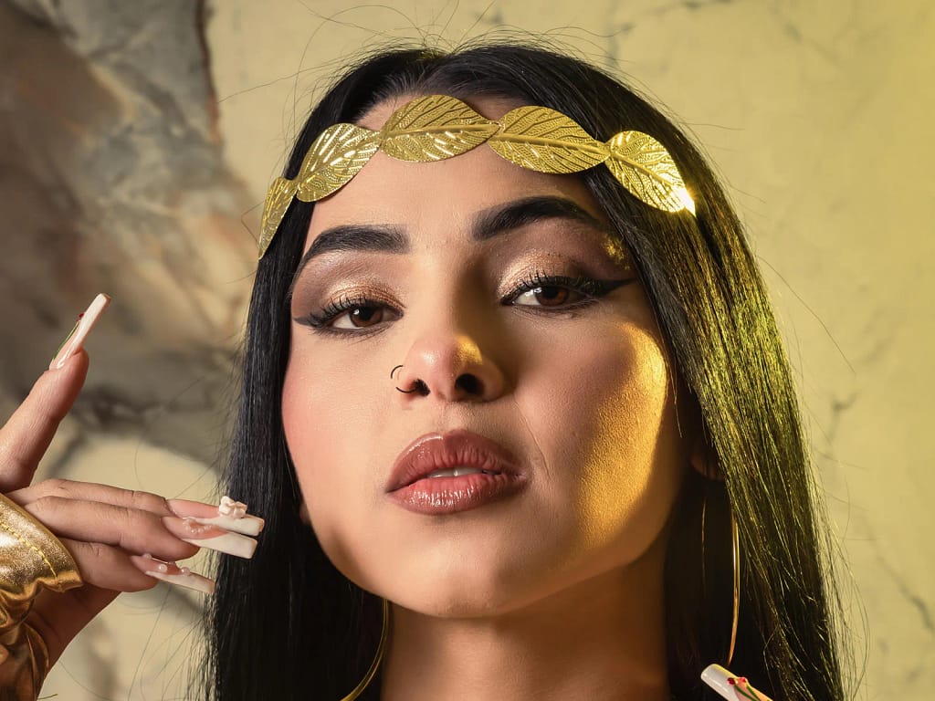 MistressAsshley holding BDSM leash, black outfit, confident pose, dark setting.