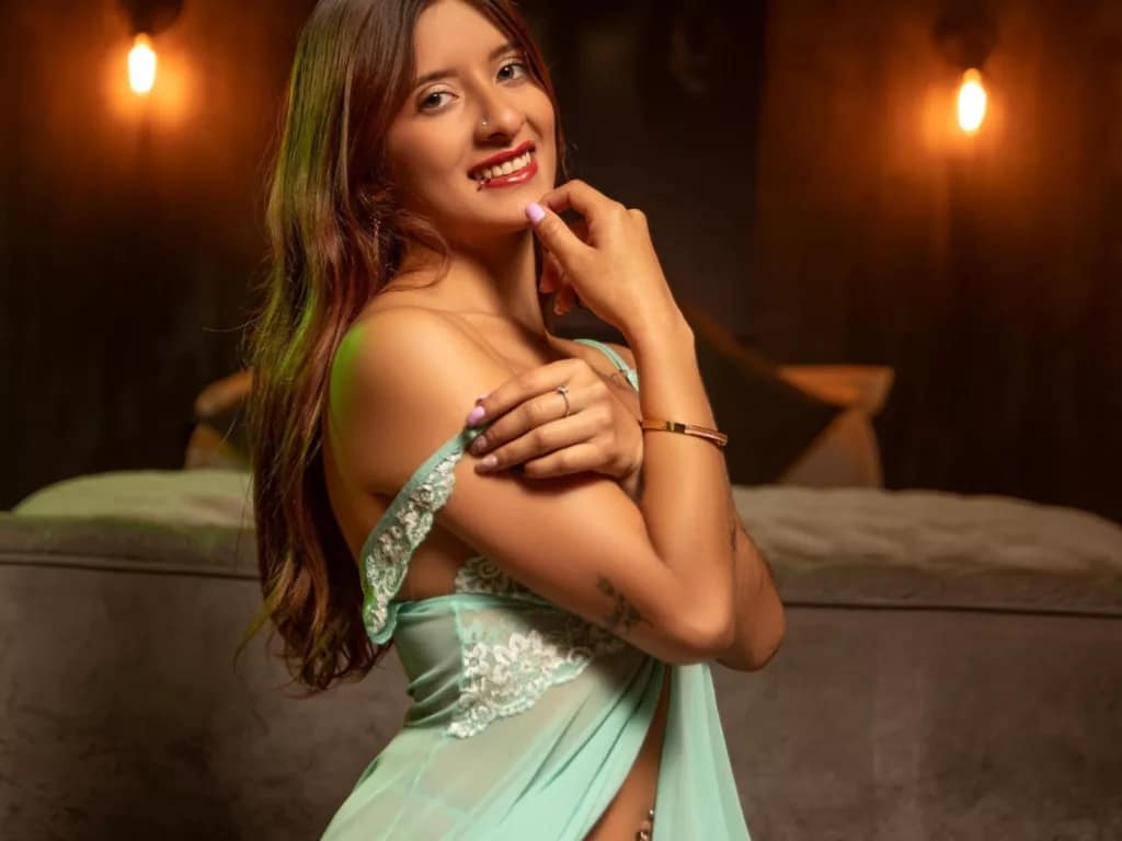 Voyeur neighbor’s dream: XimeRocks in green lace, smiling, warm lights, cozy backdrop.